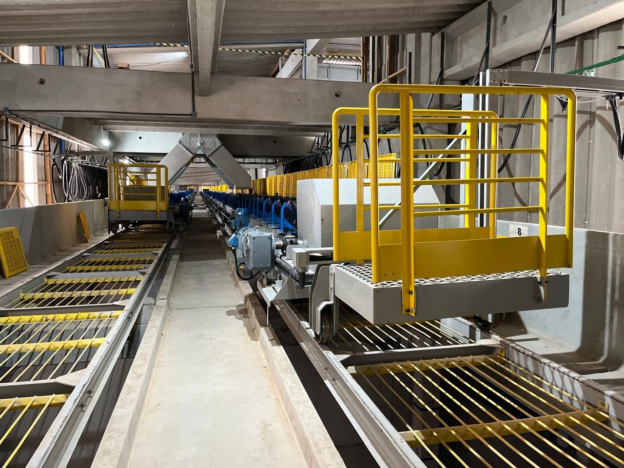 Transportador de correia com plataforma e guarda-corpo amarelo em unidade de fertilizantes