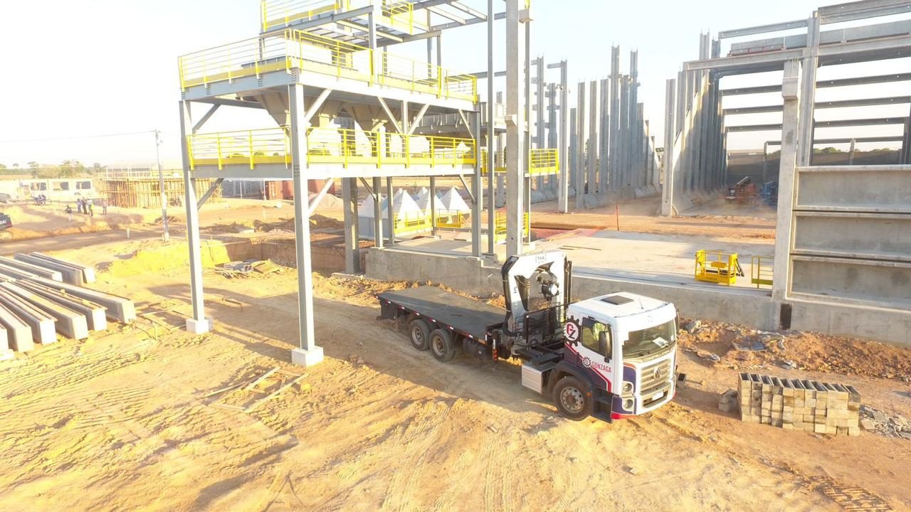Torre de elevador e moega em montagem, com caminhão de carga na obra